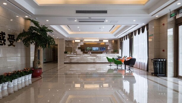 A modern hotel lobby with a reception desk, seating area, and a large potted plant. - Greentree Inn Changzhou Zhongwu Avenue Jiangsu Uni (Changzhou)