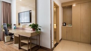 A modern hotel room with a wooden desk, a flat-screen TV, a potted plant, a chair, and a wardrobe. - Greentree Inn Changzhou Zhongwu Avenue Jiangsu Uni (Changzhou)