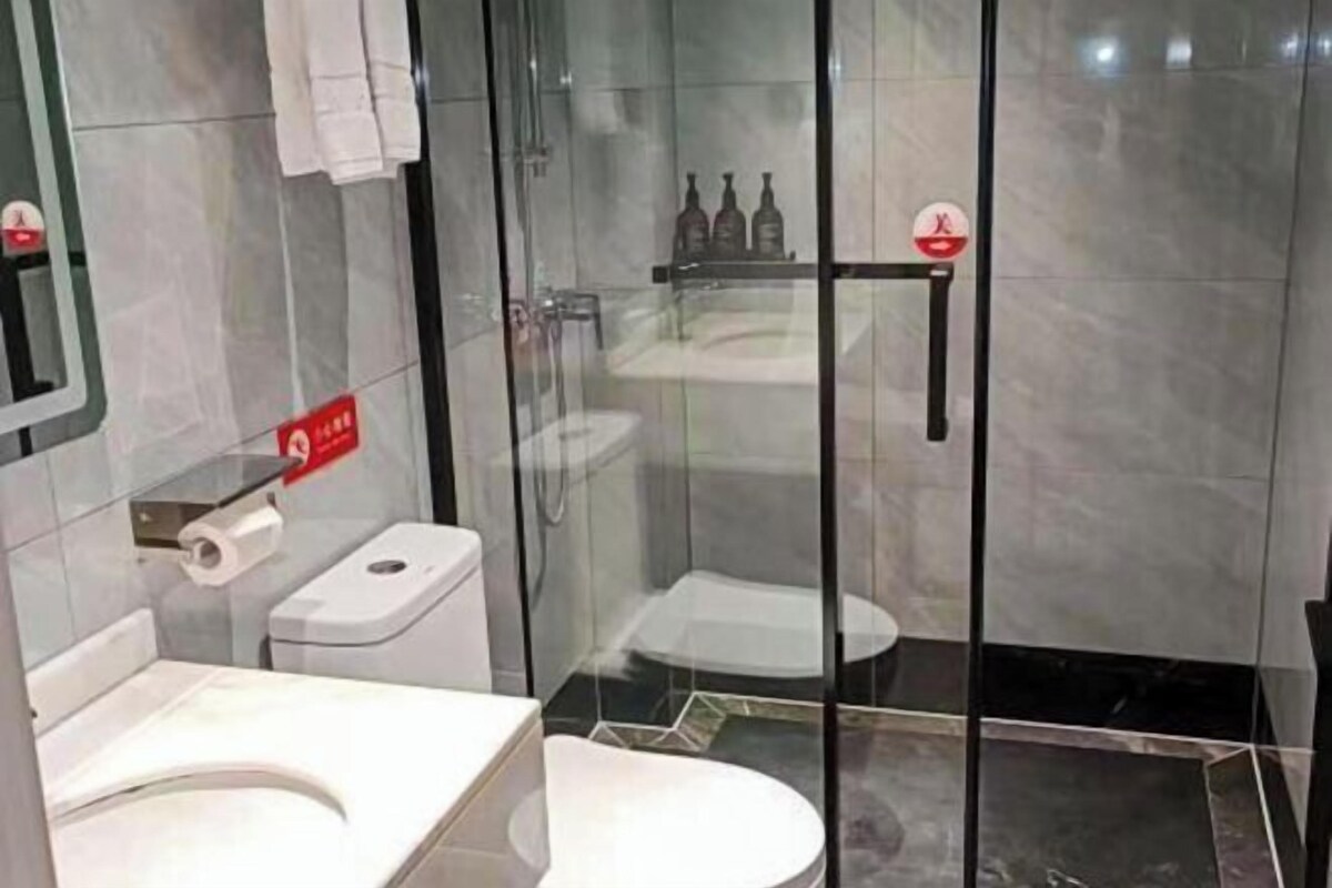 A modern bathroom with a glass-enclosed shower, a toilet, and a sink.
