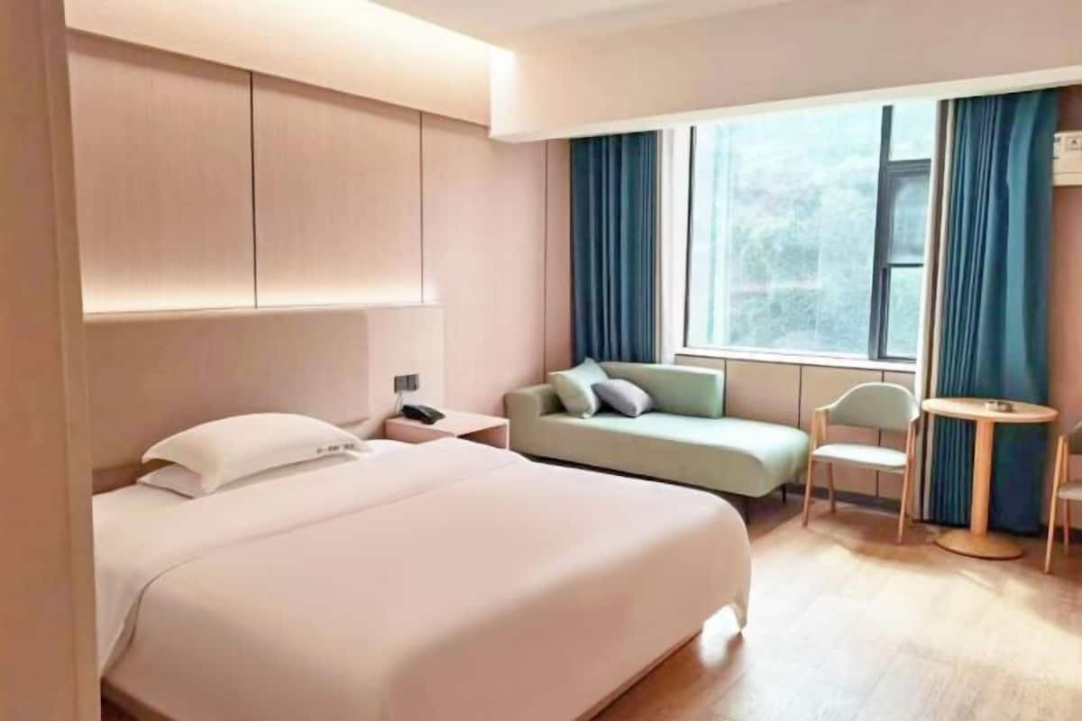 Hotellihuone, jossa on suuri sänky, sohva, pieni pöytä ja tuoli.