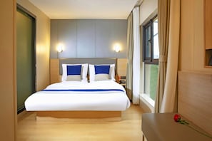 A hotel room with a large bed, bedside tables, a nightstand, a window with curtains, and a wall-mounted light fixture. - 7 Days Premium Shanghai International Automobile City Tongji University Branch (Shanghai)