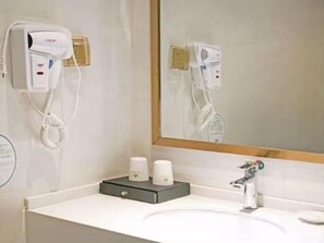 A bathroom with a white sink, a mirror, a hairdryer, and a tissue dispenser. - Greentree Inn Yingtan Xinjiang New District Munici (Yingtan)