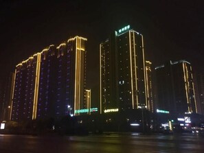A high-rise building with illuminated vertical lines and a green sign at the top. - Greentree Inn Yingtan Xinjiang New District Munici (Yingtan)