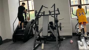 A gym with exercise equipment, including a stair climber and an elliptical machine.