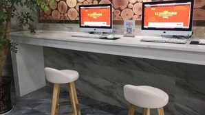 A reception desk with two computer monitors displaying a website, a marble counter, and two white bar stools. - Greentree Inn Yingtan Xinjiang New District Munici (Yingtan)