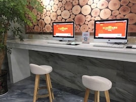 Un mostrador de recepción con dos monitores de ordenador mostrando un sitio web, una encimera de mármol y dos taburetes blancos.
