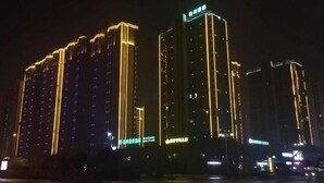 A high-rise building with illuminated vertical lines and a green sign at the top. - Greentree Inn Yingtan Xinjiang New District Munici (Yingtan)