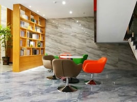 A modern library with a marble floor, wooden bookshelves, and colorful chairs.
