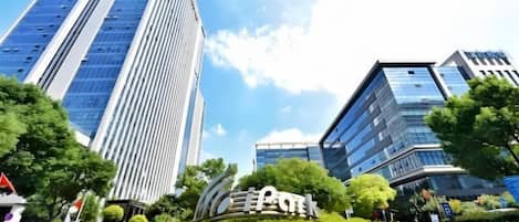 A modern urban landscape with high-rise buildings, a landscaped area with greenery, and a clear sky.