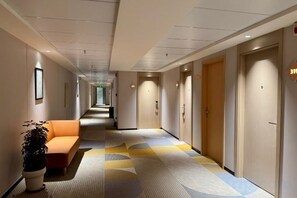 A hotel corridor with a sofa, a potted plant, and doors leading to rooms. - Jinjiang Inn (Wuxi New District National Software Park) (Wuxi)