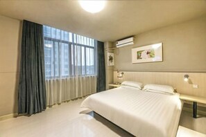 A hotel room with a large bed, a bedside table, an air conditioning unit, and a window with curtains. - Jinjiang Inn (Wuxi New District National Software Park) (Wuxi)
