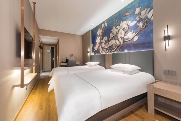 A hotel room with two beds, a wooden floor, a painting of flowers on the wall, and a desk with a chair. - Jinjiang Inn (Wuxi New District National Software Park) (Wuxi)