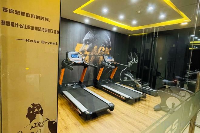 A gym with treadmills, a wall with a poster, and a mirror.