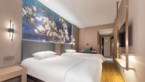 A hotel room with two beds, a large floral mural, a wooden floor, and a hallway with a mirror. - Jinjiang Inn (Wuxi New District National Software Park) (Wuxi)