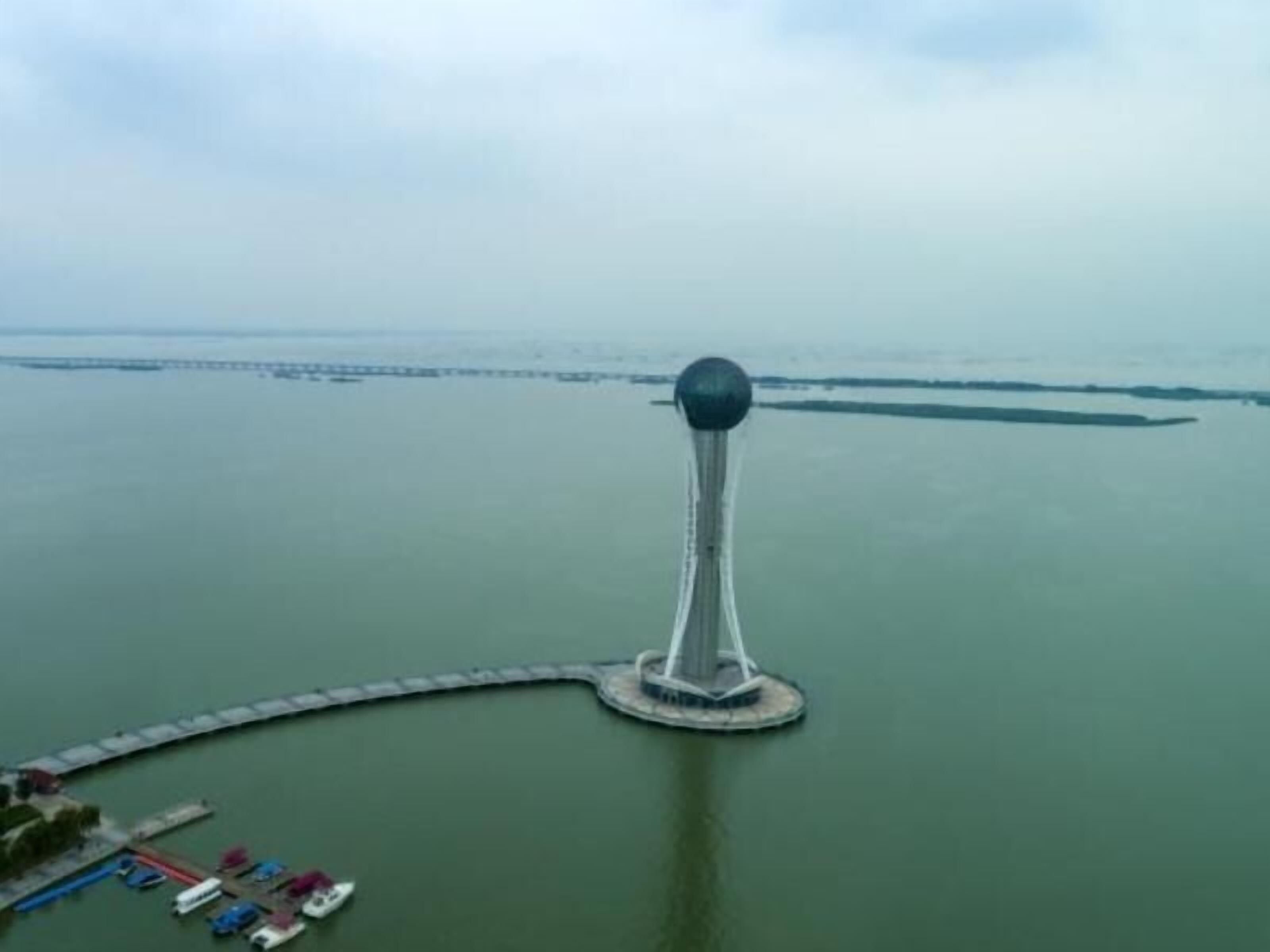 A tower with a spherical top, surrounded by a dock and a small pier with boats.