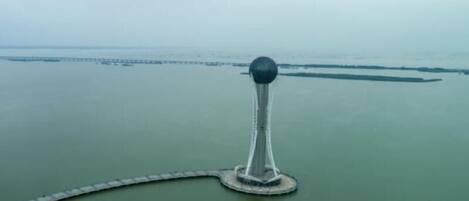 A tower with a spherical top, surrounded by a dock and a small pier with boats.