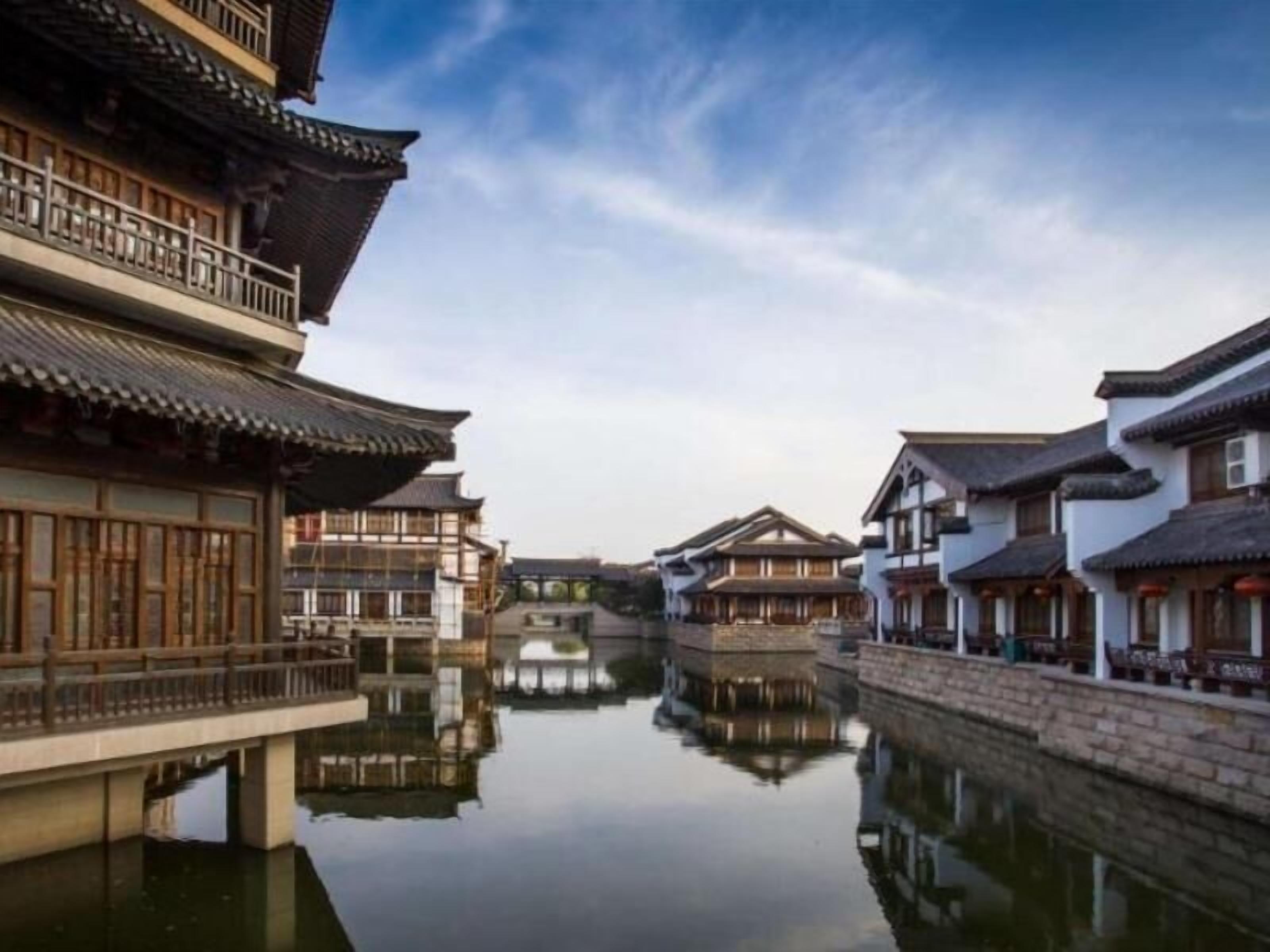 A traditional Chinese courtyard with buildings reflecting on the water.