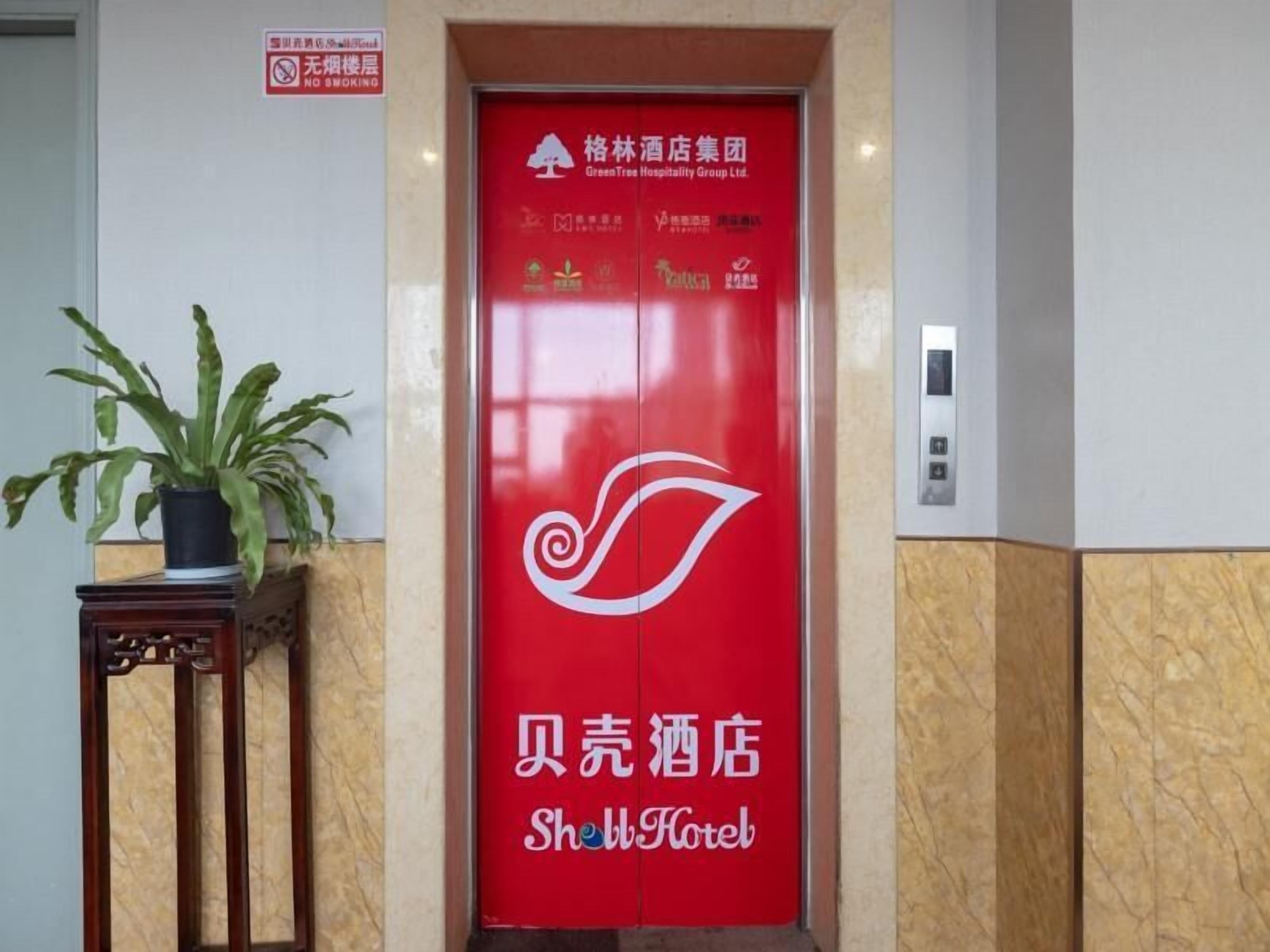 L’entrée d’un hôtel, avec une porte rouge sur laquelle figure le nom de l’hôtel en chinois et en anglais.