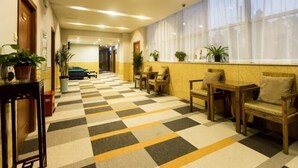 A hotel lobby with a checkered floor, seating area with chairs and tables, potted plants, and a large window with sheer curtains. - Shell Changzhou University City Science and Educat (Changzhou)