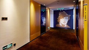 Un pasillo con piso alfombrado, un letrero de salida instalado en la pared y un retrato iluminado de gran tamaño a la derecha.