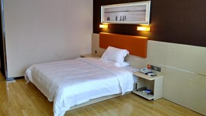 Habitación de hotel con cama, mesita de noche, teléfono y lámpara fijada en la pared.