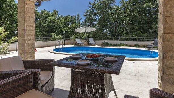 An outdoor patio with wicker furniture, a pool, and a covered area with stone pillars. - Luxury Villa Lucia with heated pool (Vodnjan)