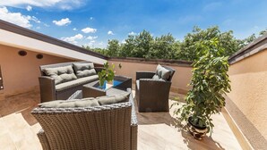 A rooftop patio with wicker furniture, a glass-top table, and a potted plant. - Luxury Villa Lucia with heated pool (Vodnjan)