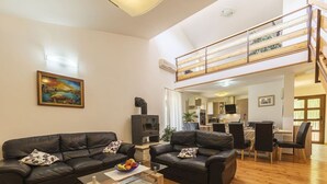 A spacious living area with two black leather sofas, a coffee table, and a dining area with chairs and a table. A staircase leads to an upper level. - Luxury Villa Lucia with heated pool (Vodnjan)