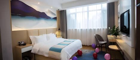 A modern hotel room with a large bed, a desk, a chair, a television, and a large window with curtains.