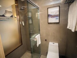 Un baño con cabina de ducha de vidrio, inodoro y un cuadro en la pared.