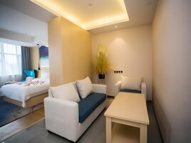 Una habitación de hotel moderna con una cama, un sofá, una mesita y una planta decorativa.