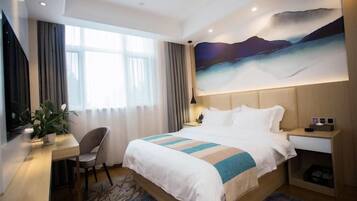 A hotel room with a bed, desk, chair, and a large painting on the wall.