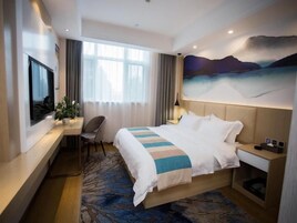 Una habitación de hotel con cama, escritorio, televisor y un cuadro en la pared.