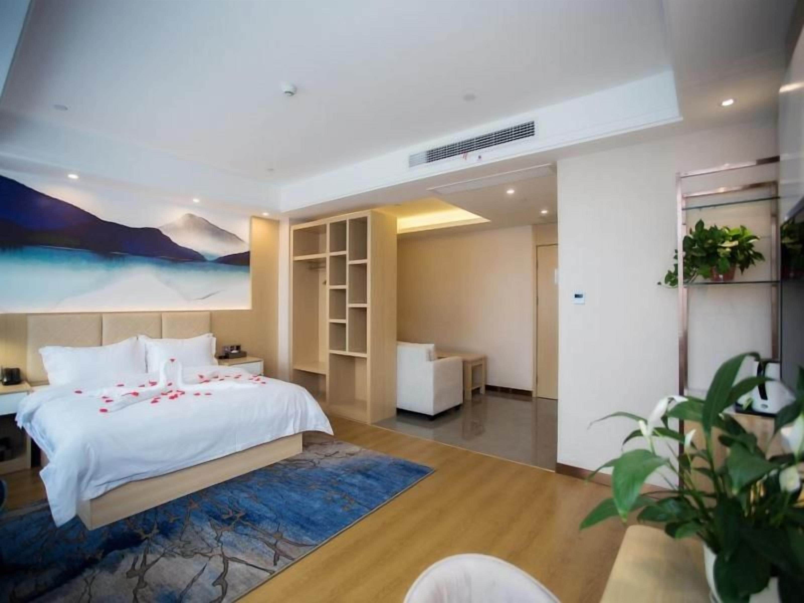 Quarto de hotel moderno com cama, mesa de cabeceira e uma janela grande.