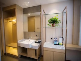 A modern bathroom with a double sink, a glass shelf with toiletries, and a shower area.