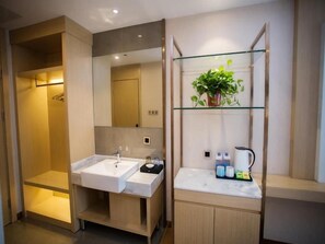 A modern bathroom with a double sink, a glass shelf with toiletries, and a shower area.