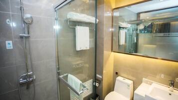 Un baño moderno con cabina de ducha de vidrio, inodoro y lavamanos.