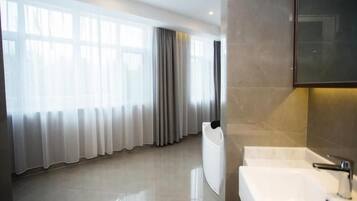 A modern bathroom with a large mirror, a white sink, and a glass shower enclosure.