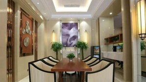A dining area with a central table surrounded by chairs, a large abstract painting on the wall, and two potted plants. - Jinjiang Inn Select (Wuhan International Expo Center Maying Road Metro Station) (Wuhan)