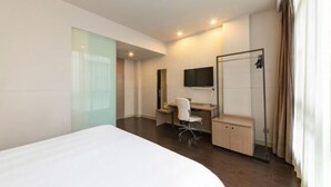 A modern hotel room with a large bed, a desk with a chair, a TV, and a shower area. - Jinjiang Inn Select (Wuhan International Expo Center Maying Road Metro Station) (Wuhan)