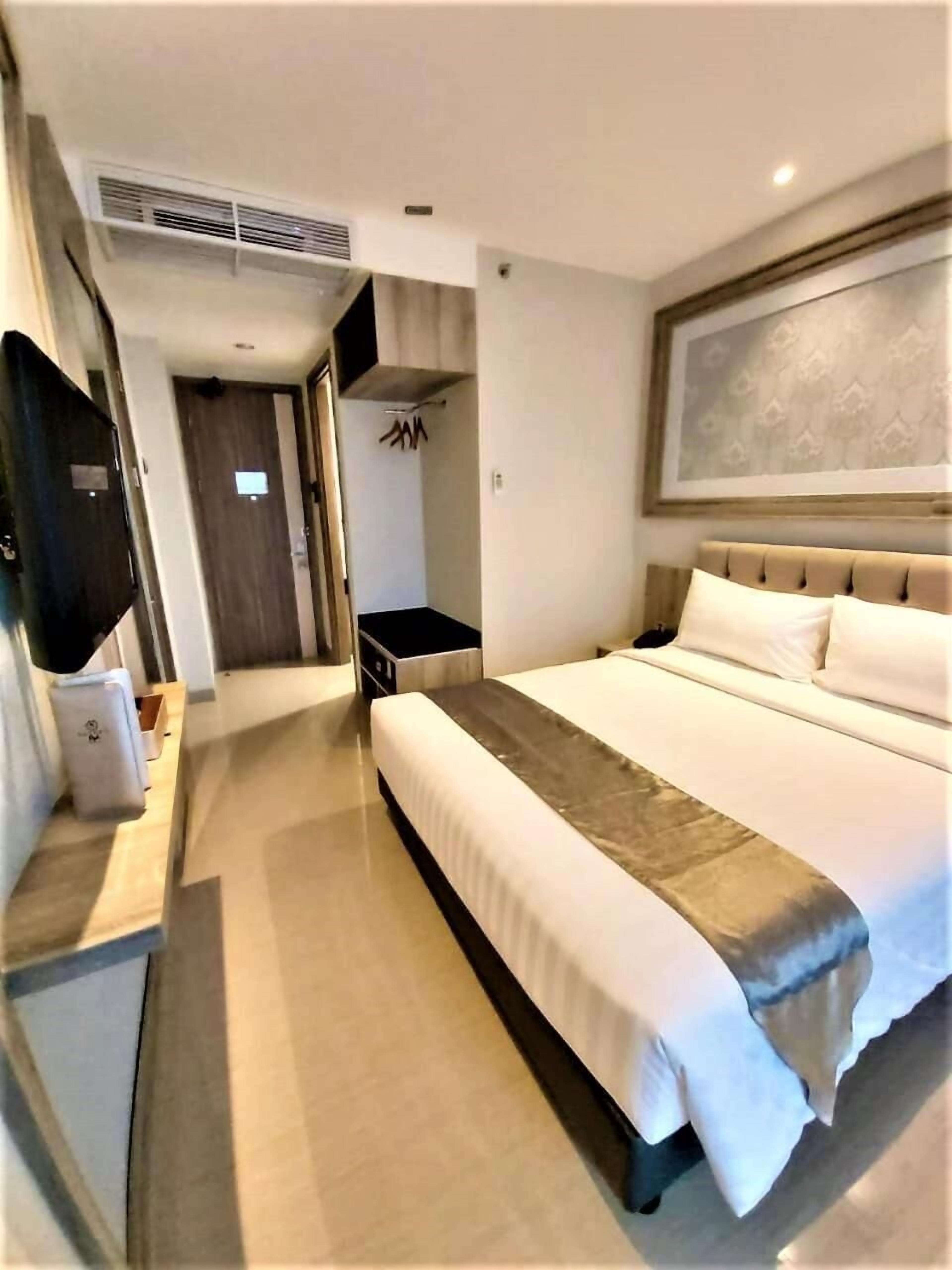 Ein Hotelzimmer mit einem großen Bett, einem an der Wand befestigten Flachbildfernseher, einem Kleiderschrank und einer Tür zu einem Badezimmer.