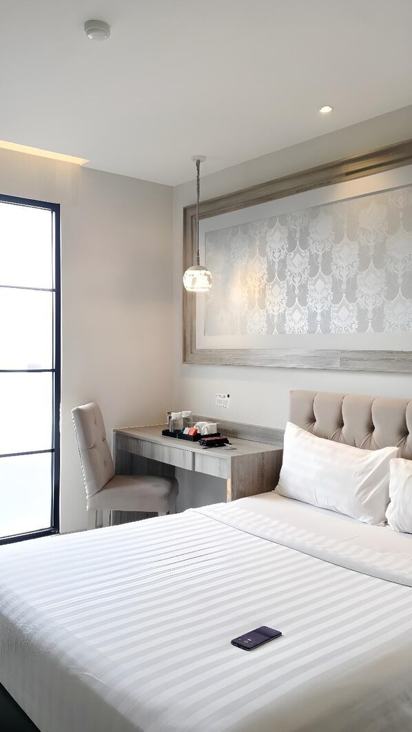 A modern hotel room with a large bed, a desk, and a chair. - Savero Style Hotel Bogor (Bogor)