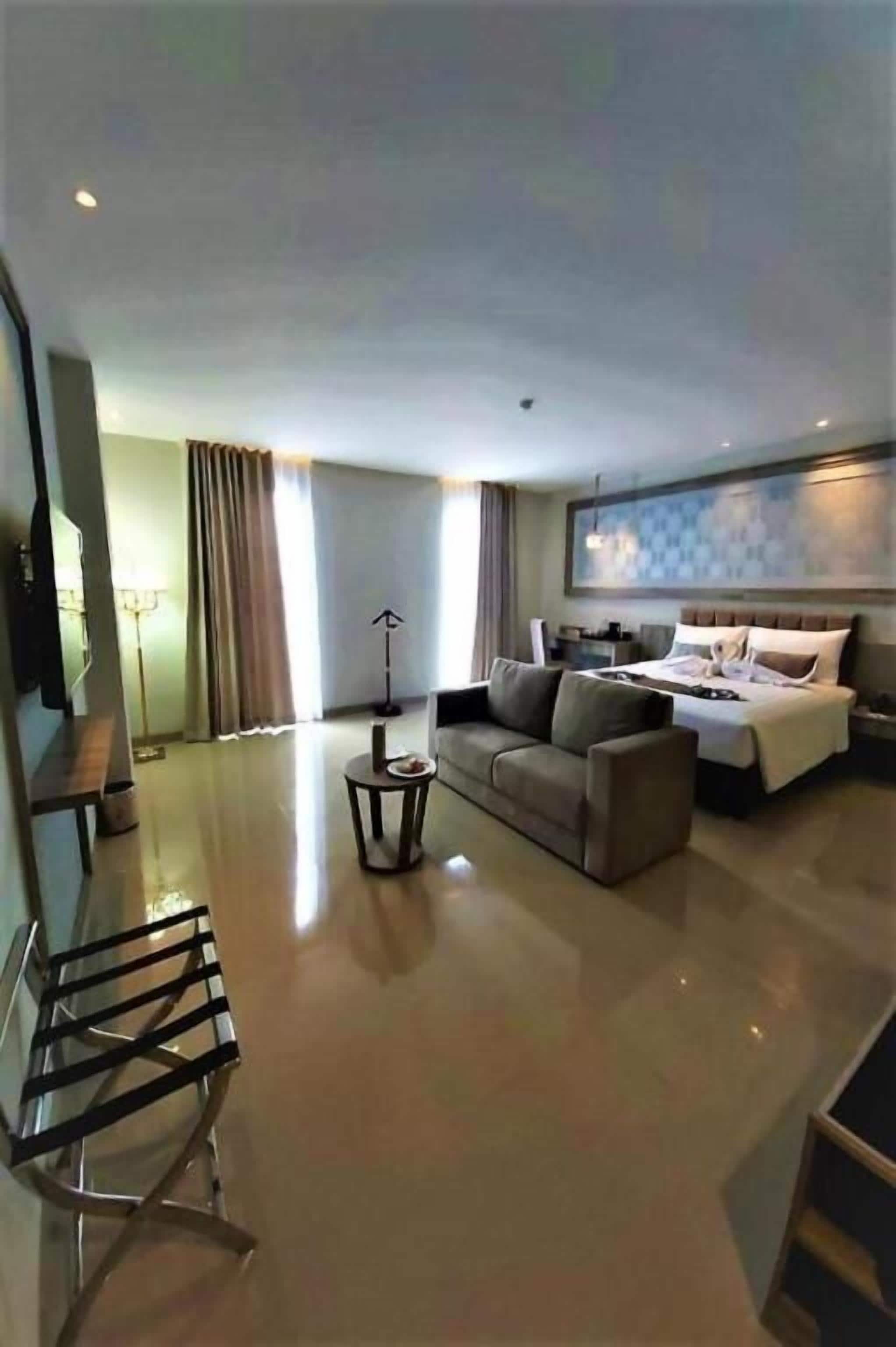 A hotel room with a bed, a sofa, a coffee table, and a desk.