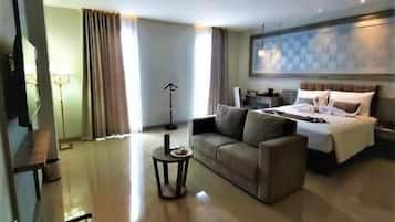 A hotel room with a bed, a sofa, a coffee table, and a desk.
