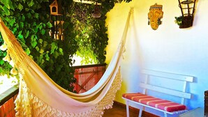 A hammock, a bench, and a wall with hanging lanterns and greenery. - Monte Alentejano T5 Private Pool (Portalegre)