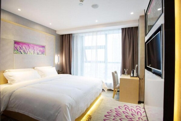 A hotel room with a large bed, a desk, a chair, a TV, and a window with curtains. - Lavande Hotels (Chengdu)