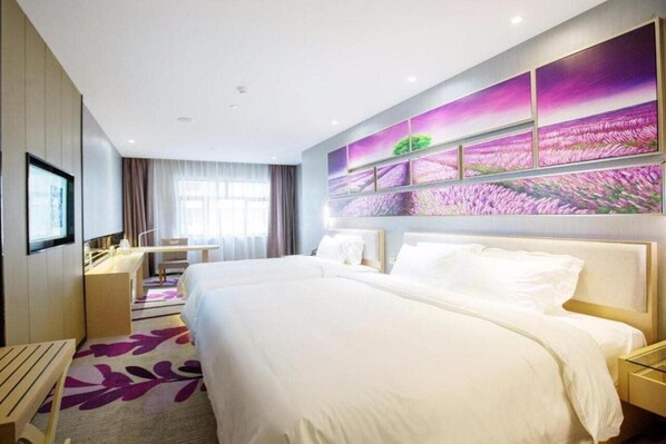 A hotel room with a large bed, a desk, and a chair. There is a large window with curtains, and a wall with a floral painting. - Lavande Hotels (Chengdu)