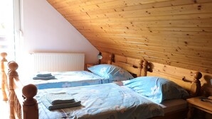 Een slaapkamer met twee bedden, houten hoofdeinden, een radiator en een lamp.