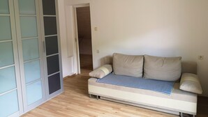 Een kamer met een bank, een schuifglasdeur en een houten vloer.