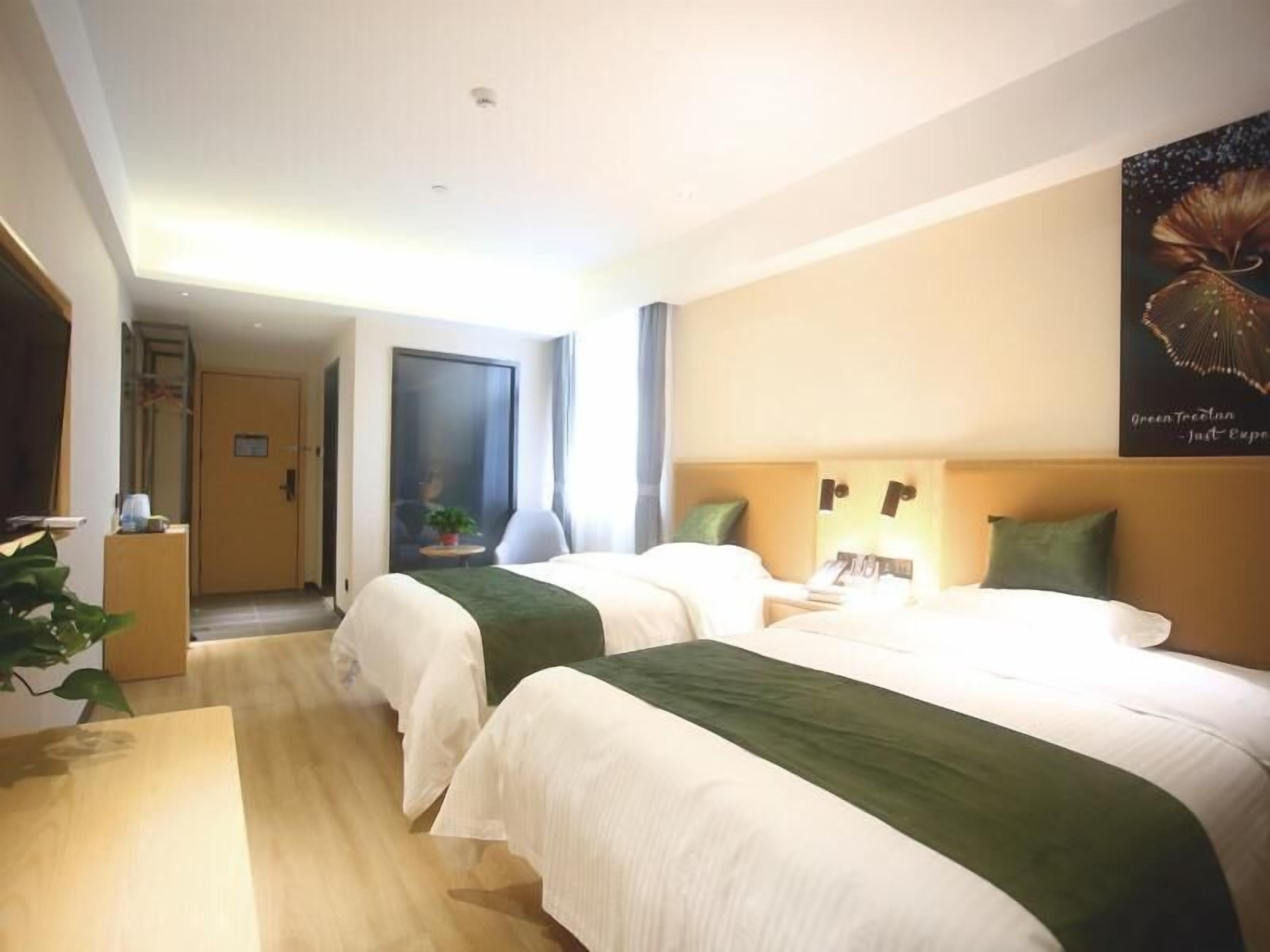 Habitación de hotel con dos camas, un escritorio y un ventanal grande.